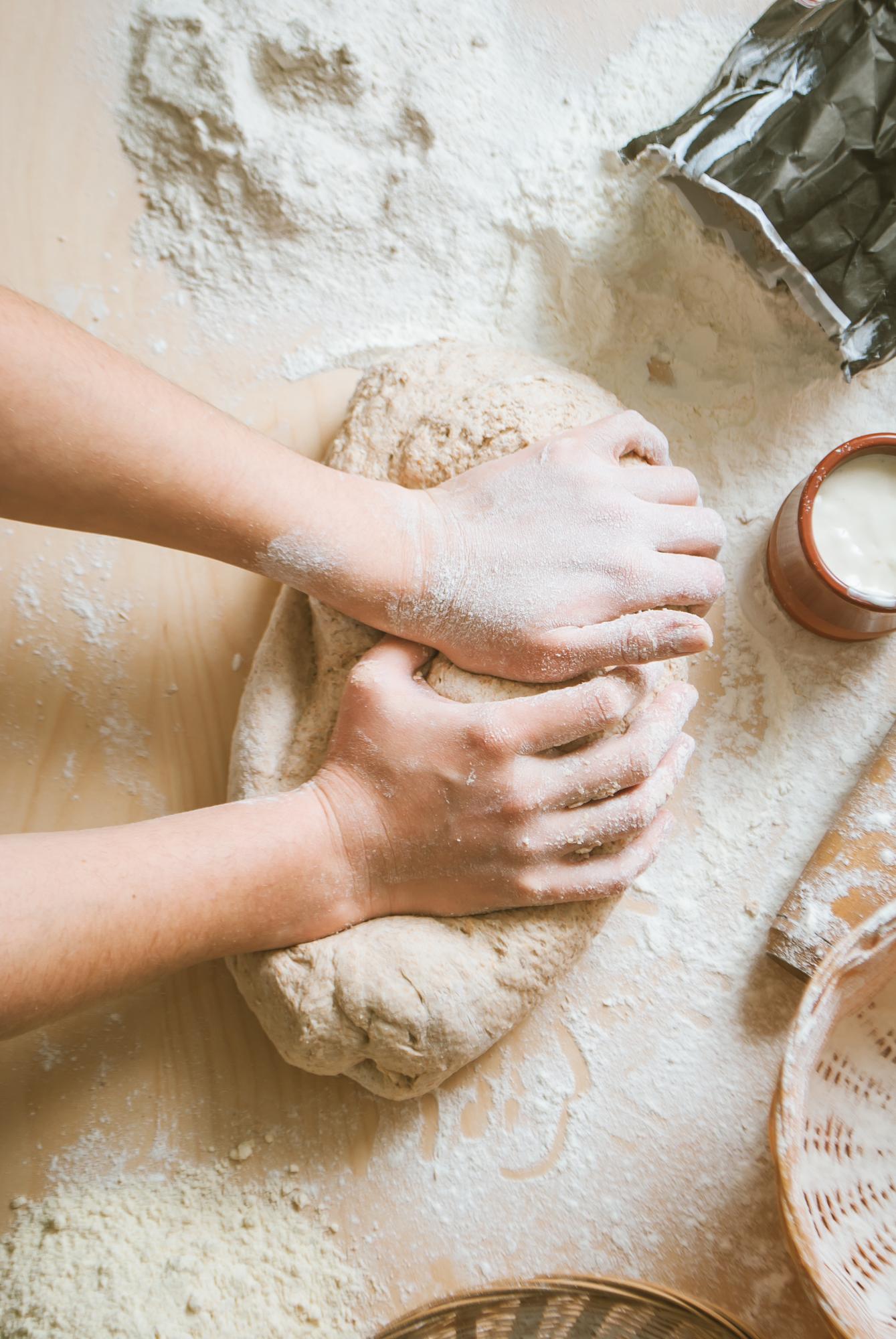 Close-up of hands kneading dough with flour dust