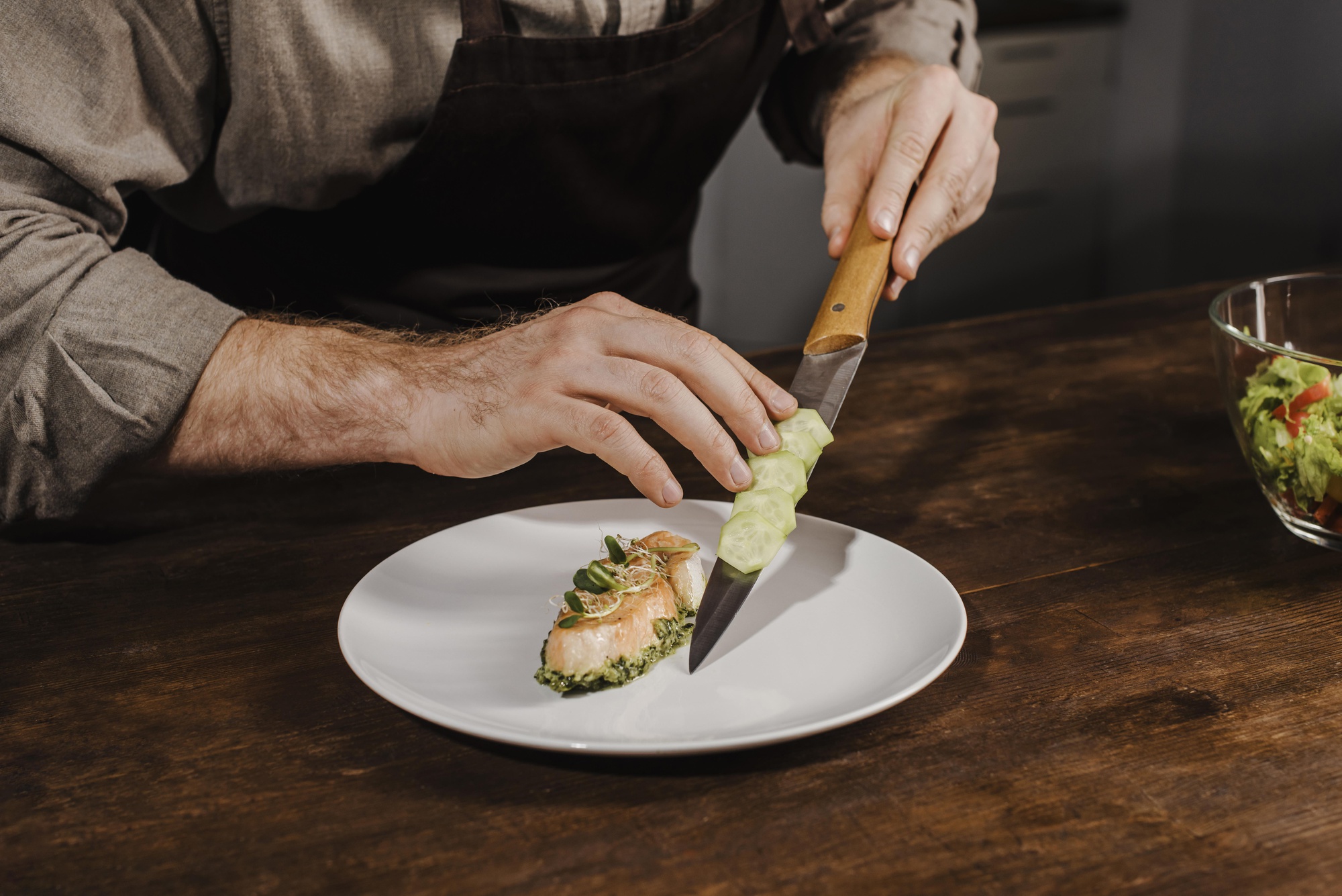Chef arranging a simple plated dish on wooden table